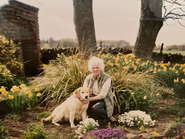 Jessie Scott kneeling in a farmhouse garden with a labrador dog