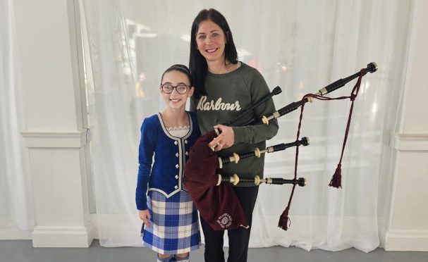 Eve Muirhead holding bagpipes next to Mille Nicolson in Scottish country dancing dress