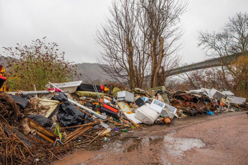 Large piles of illegally dumped waste beside roadside under Perth's Friarton Bridge.