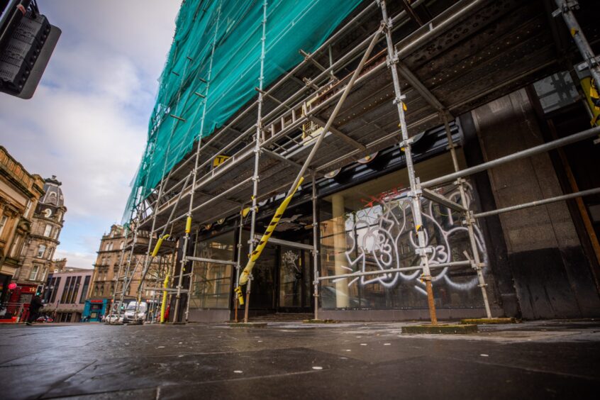 Picture shows outside premises of 1a High Street with scaffolding covering the entrance and the windows tagged with graffiti.