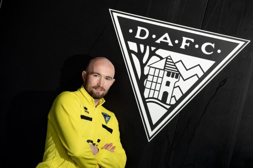 Chris Kane stands beside a large Dunfermline Athletic F.C. badge.