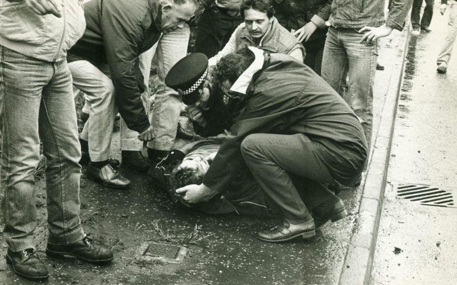 Police and miners tend a picket injured during a clash in the Dunfermline area.