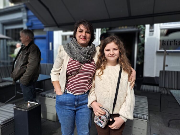 Carina Wilson with short dark hair, stripy top and arms around Gabriella, who has long fair curls