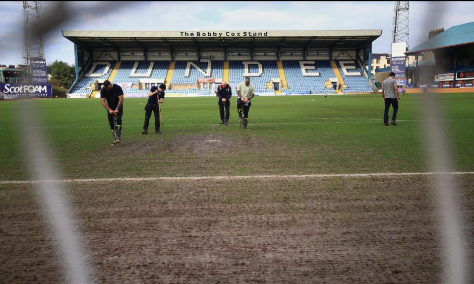 Staff work on the pitch at Dens Park. Image: Shutterstock