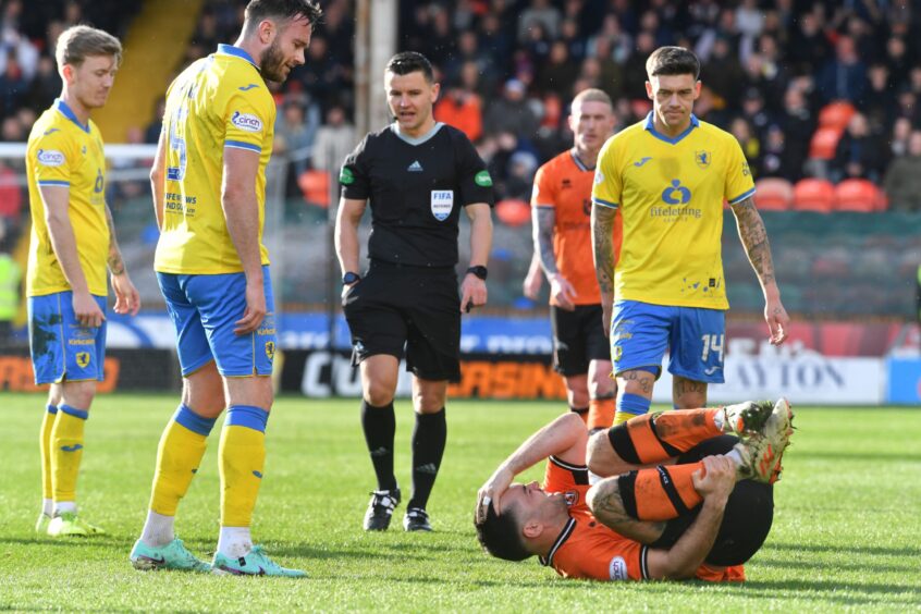 Dundee United striker Tony Watt lies on the ground holding his head and his shin as Raith Rovers trio Kyle Turner, Keith Watson and Josh Mullin look down at him.