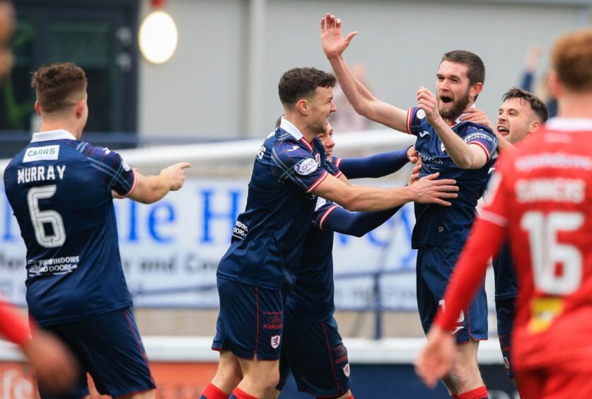 Sam Stanton smiles and throws his hands in the air as his Raith Rovers team-mates rush to celebrate his opening goal against Dunfermline Athletic.