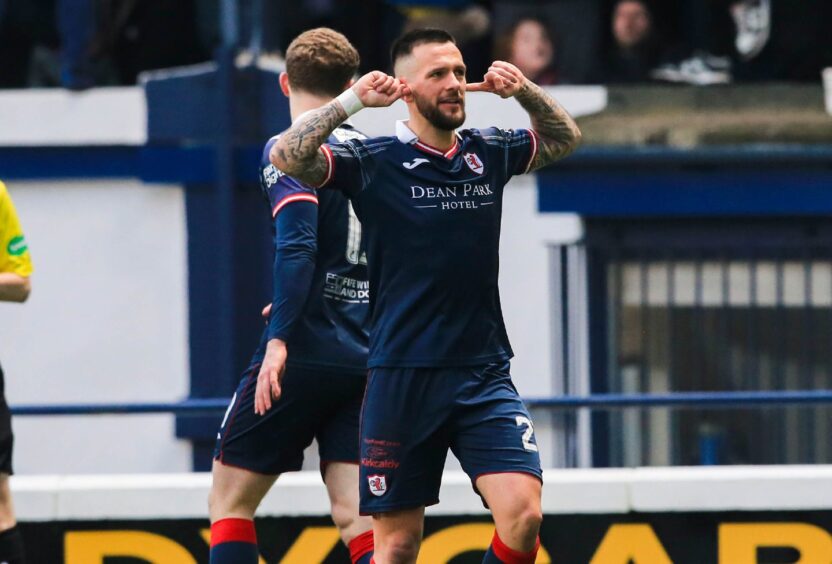 Dylan Easton puts his fingers in both ears as he celebrates a goal in front of the Raith Rovers supporters.