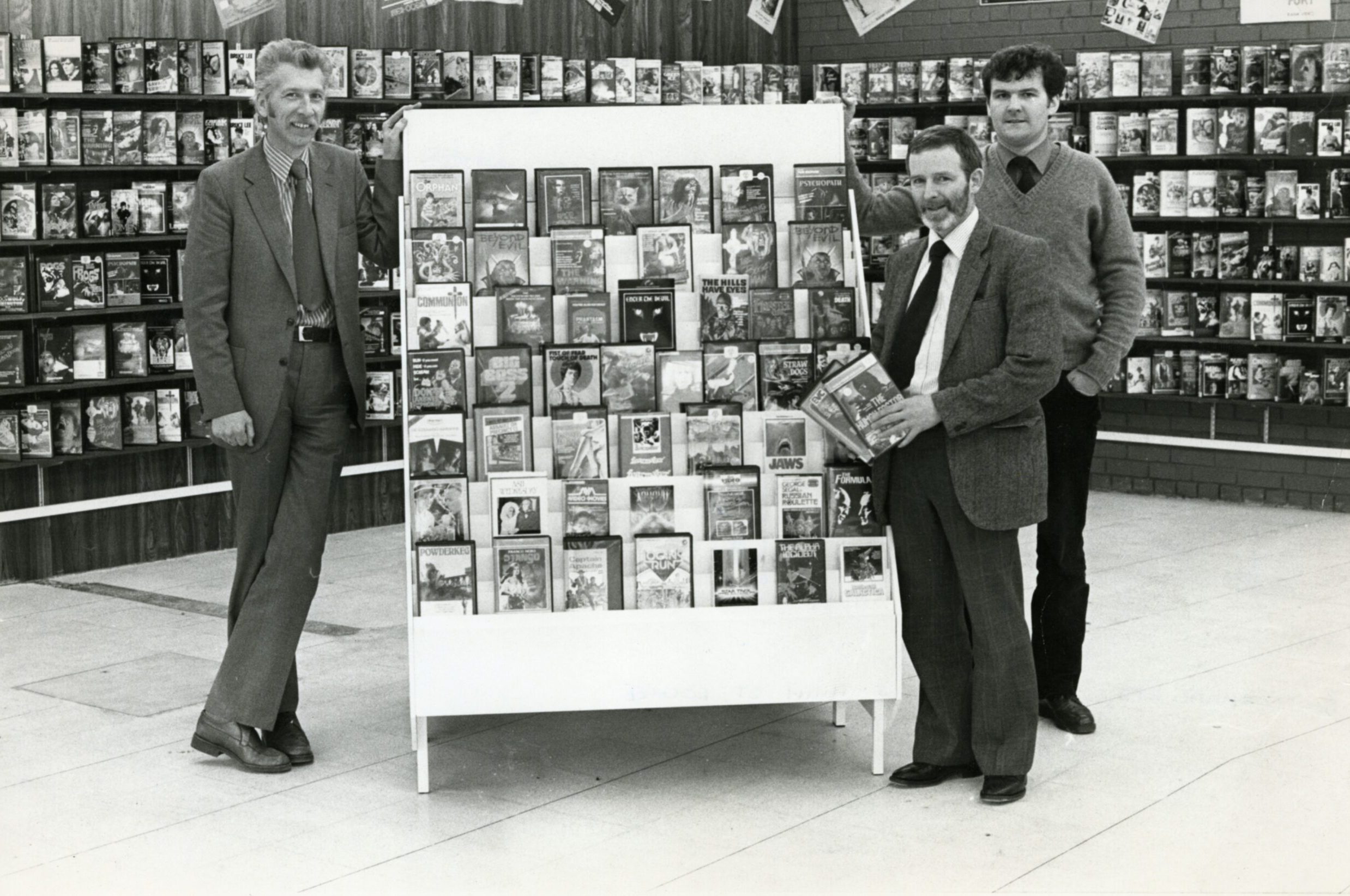 Staff beside some of the videos for hire in Lochee in 1982.