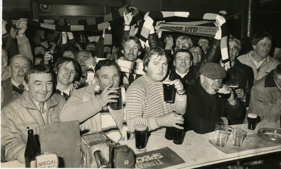 Dundee United fans crowded around the bar as they celebrate their team's win in the Athletic pub.
