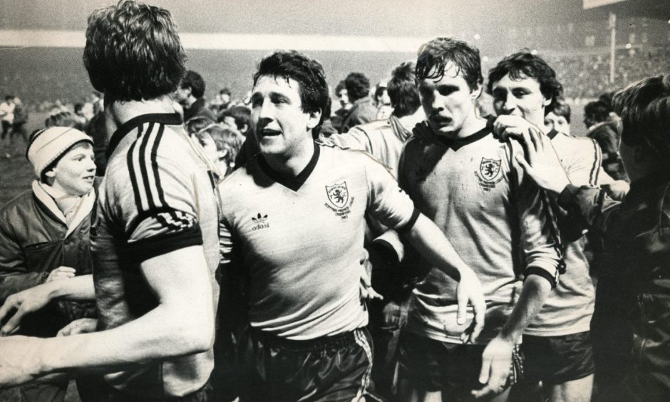 The Dundee United players celebrate on the pitch with the fans.