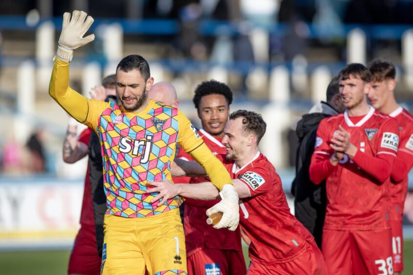 Dunfermline goalkeeper Deniz Mehmet raises his right arm in acknowledgement as he reluctantly takes the acclaim of the Dunfermline supporters after the victory away to Morton.