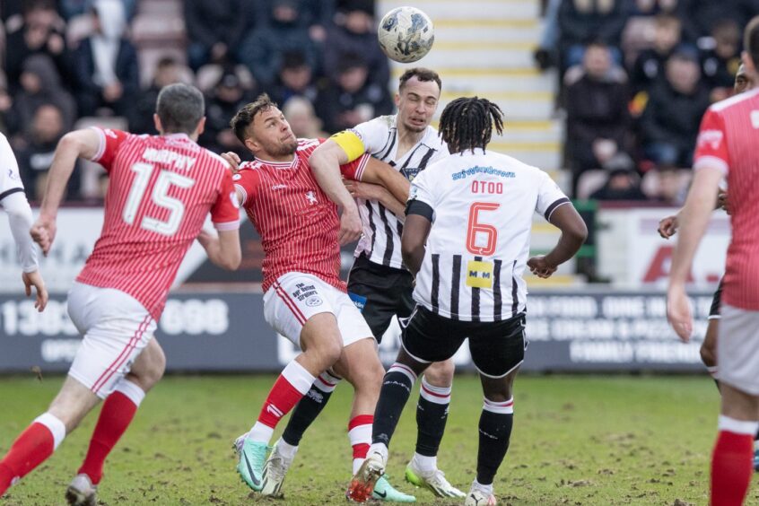 Dunfermline defender Chris Hamilton holds off an opponent to get his head to ball in the match against Ayr United as team-mate Ewan Otoo watches on.