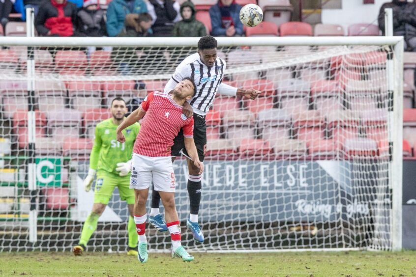 Dunfermline Athletic F.C. defender Malachi Fagan-Walcott rises high above an Ayr United attacker to head the ball clear.