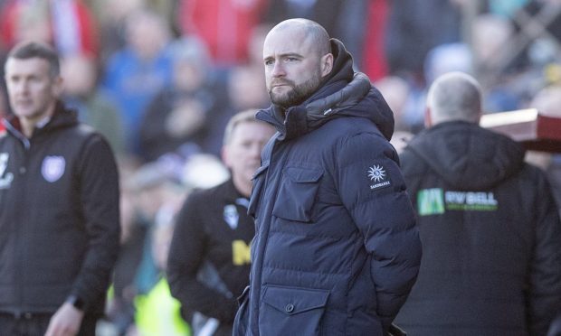 Dunfermline manager James McPake stands on the touchline with his hands behind his back.