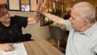 Carer high fiving patient across table.