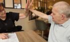 Carer high fiving patient across table.