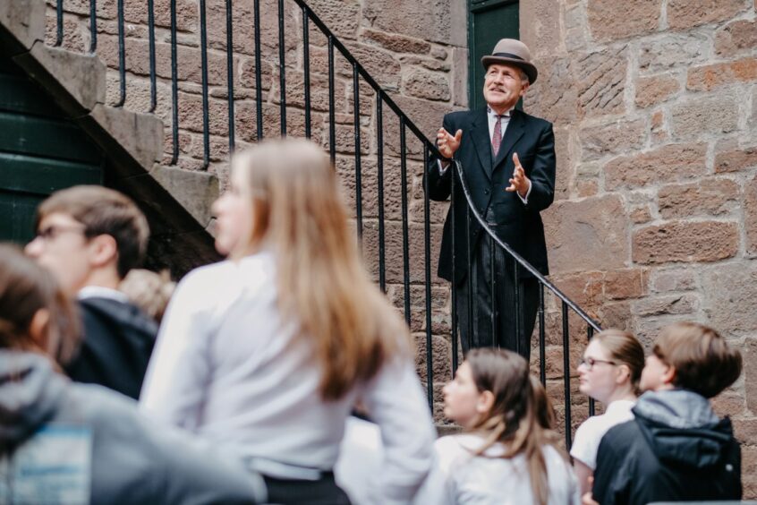 man in costume speaks with gathered children and visitors at Verdant Works