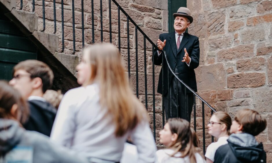 man in costume speaks with gathered children and visitors at Verdant Works