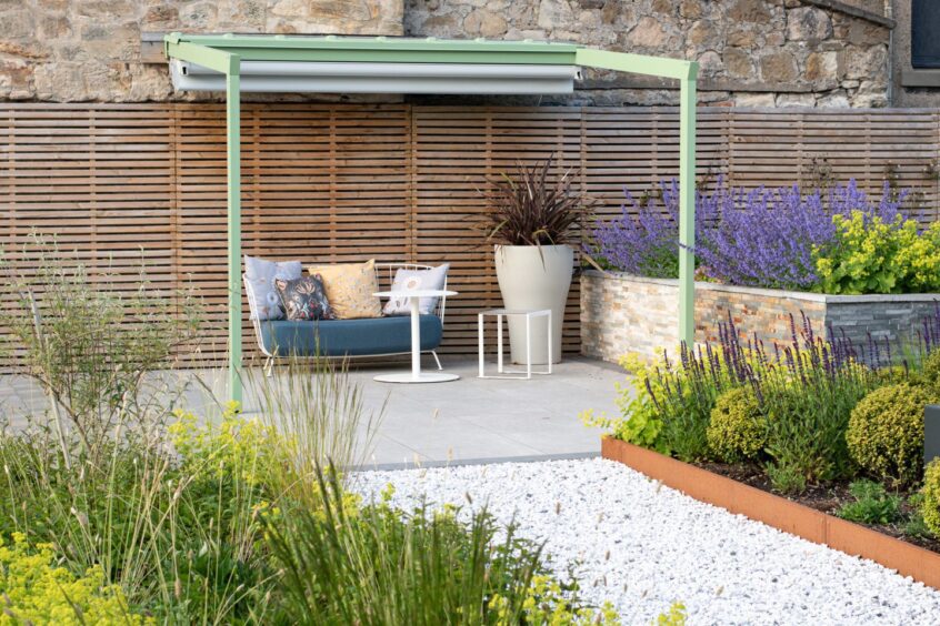 a beautifully landscaped outdoor space with pergola and seating area