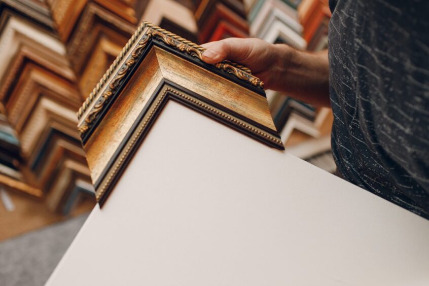 person holds a sample frame against a blank canvas