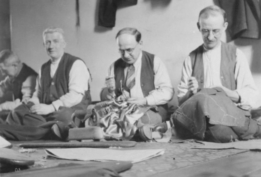 Four tailors in a row, working on clothes