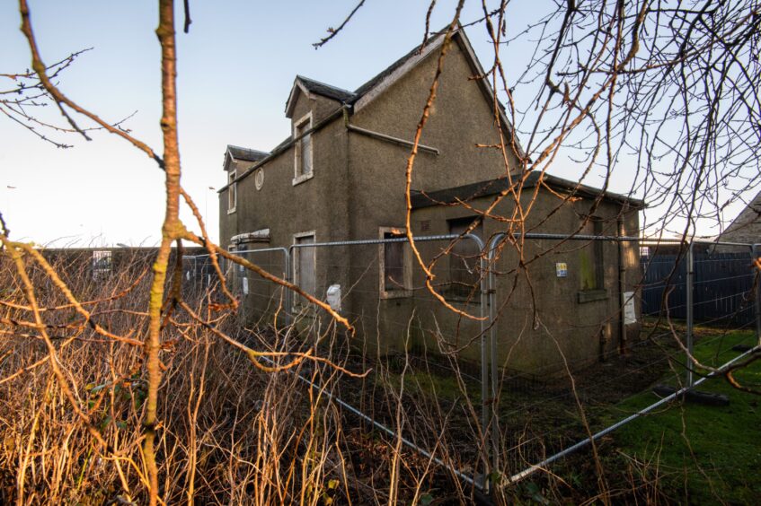 A fence surrounds the derelict Crossroads Station building