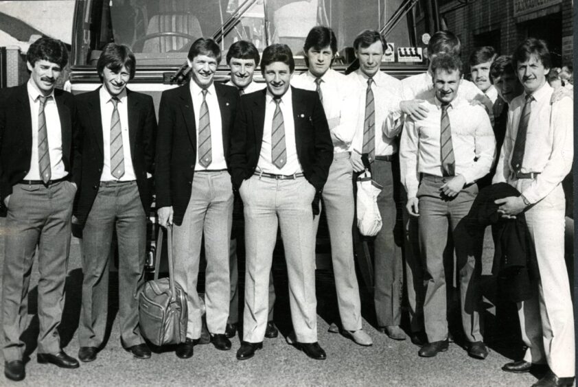 The Dundee United squad ready to head off for Italy for the second leg. They are in suits and standing in front of the team bus.