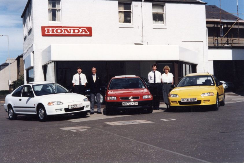 Staff members pose with three Honda cars