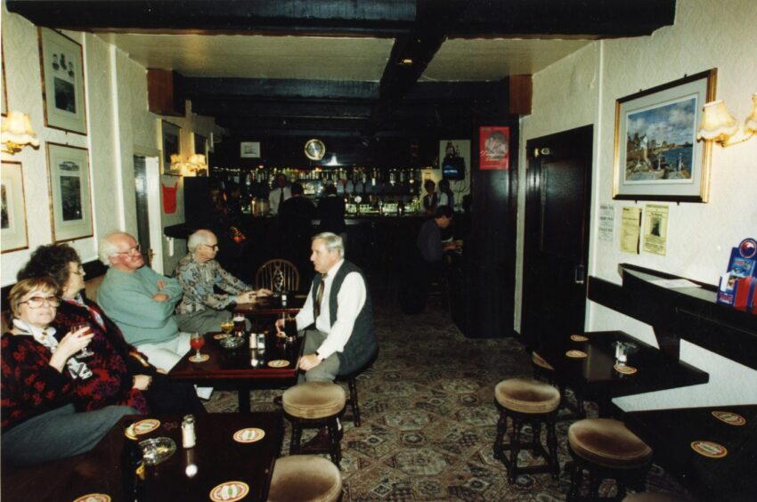 People sit around a table, with the bar visible in the background, at The Ferry Inn 