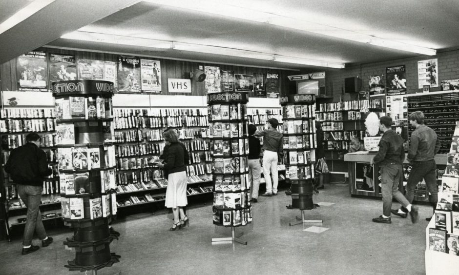 Customers look at the walls of VHS tapes in Cherry Video in Lochee