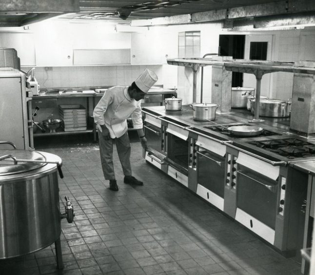 A chef in his whites inspects an oven in the kitchen in the Angus Hotel in March 1964. 