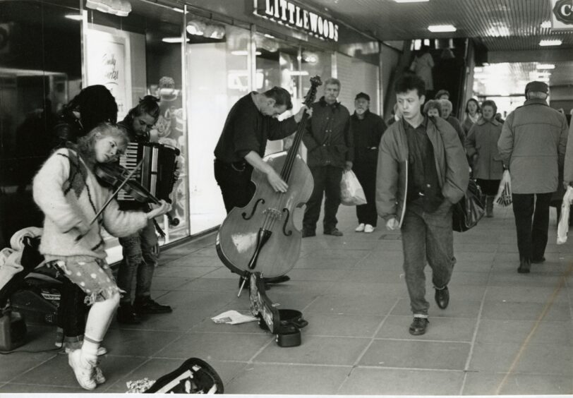 A man walks past buskers in The Overgate Centre in Dundee