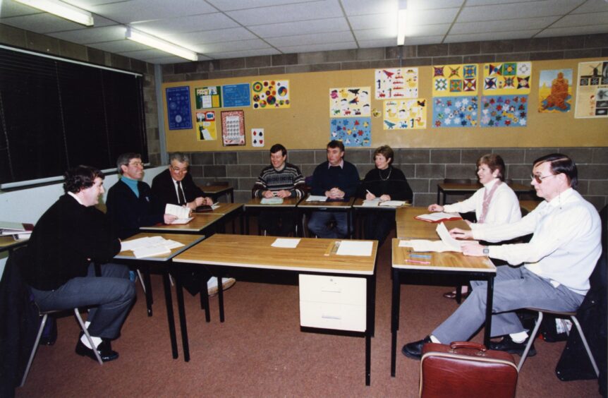 People sitting at school tables as a meeting taking place in 1994. 