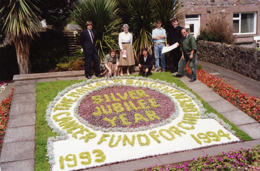 People stand beside the floral display at Monifieth by Dundee District Council. 