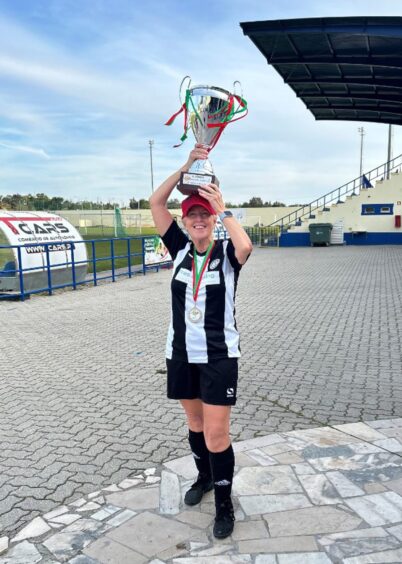 Joan Smith holding trophy over her head in black and white Jeanfield Swifts kit