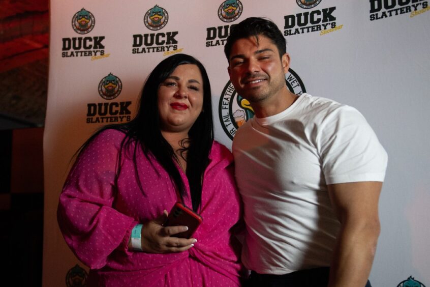 A fan wearing a pink dress poses with Love Island star, Anton Danyluk. 