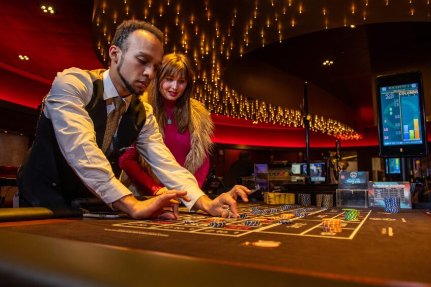 Croupier Jordon demonstrates the correct technique for clearing chips on the roulette table at Grosvenor Casino in Dundee. 