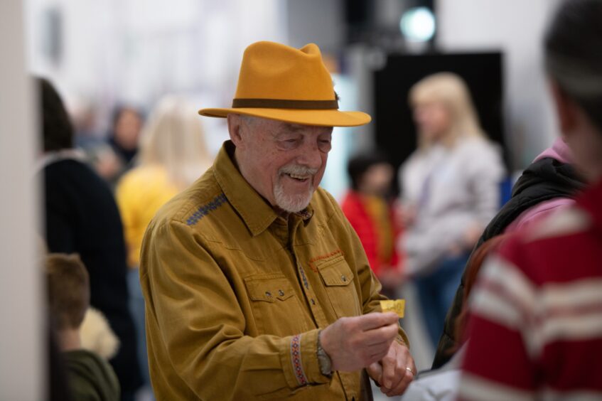 Older man in yellow shirt and hat with a yellow raffle ticket