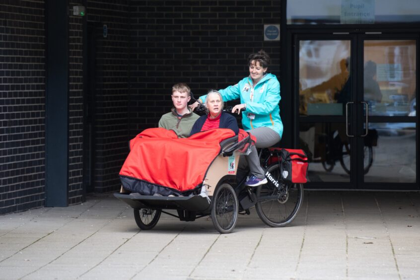 Trishaw rider carrying two passengers in the Loch Leven community campus courtyard