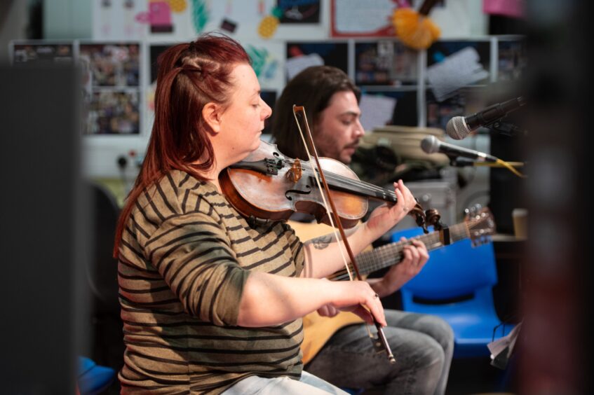 Two people playing guitar and violin at the Kinross event