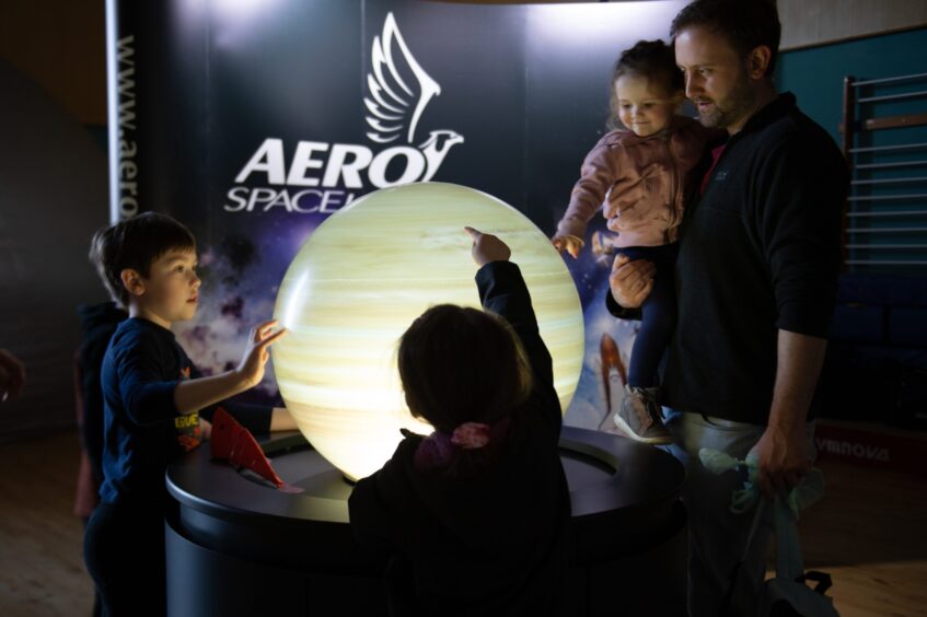 Children around an illuminated model of a planet