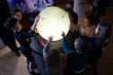Children gathered around a glowing model of the moon