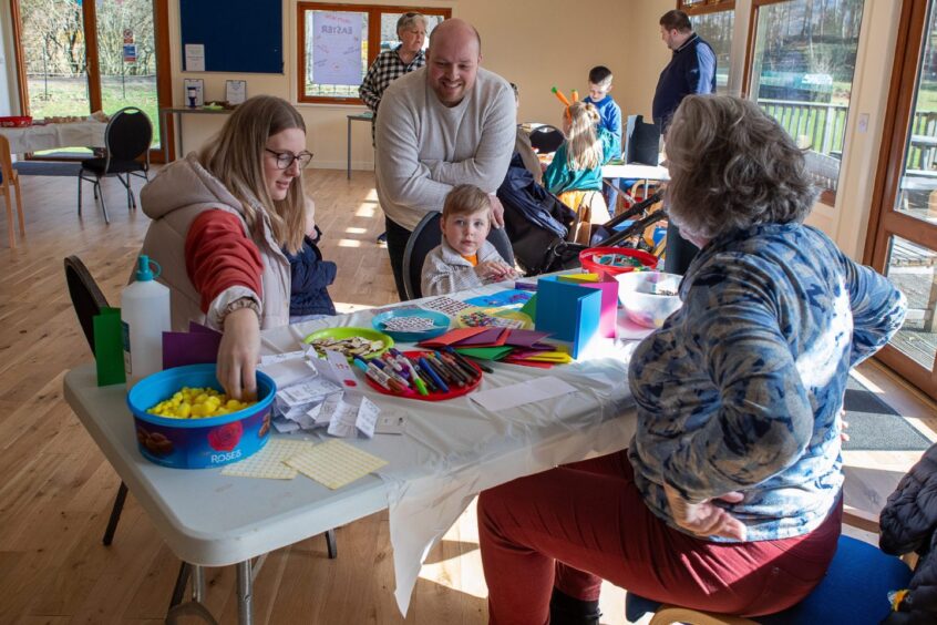 Family seated at table with colourful craft materials in Kenmore