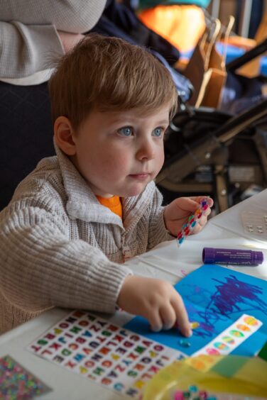 Toddler Thomas Dixon with colourful papers and easter egg stickers