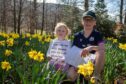 Children Grace and Christopher Tarver with sheet of clues sitting in field of daffodils at Kenmore