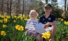 Children Grace and Christopher Tarver with sheet of clues sitting in field of daffodils at Kenmore