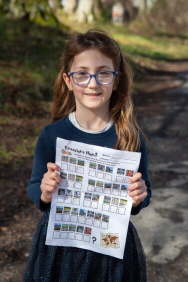  Isabella Leighton, young girl wearing glasses and blue dress, holding treasure hunt clue sheet