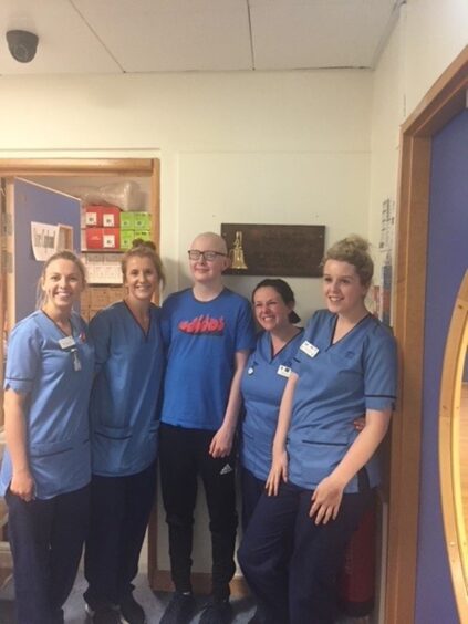 Kieran Thow as a teenager with hospital staff, posing for a group shot on a hospital ward