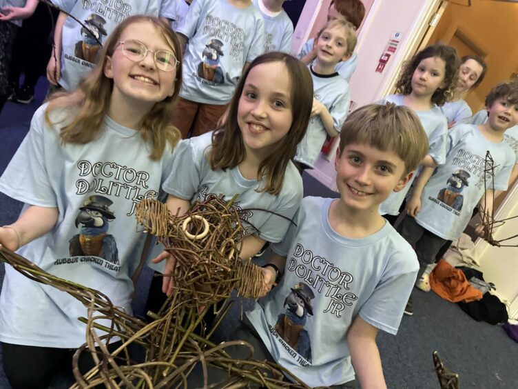 Three young children, Emma Russell, Greer Christie and Toby Menzies, holding a willow animal