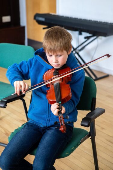 Young boy deep in concentration playing fiddle